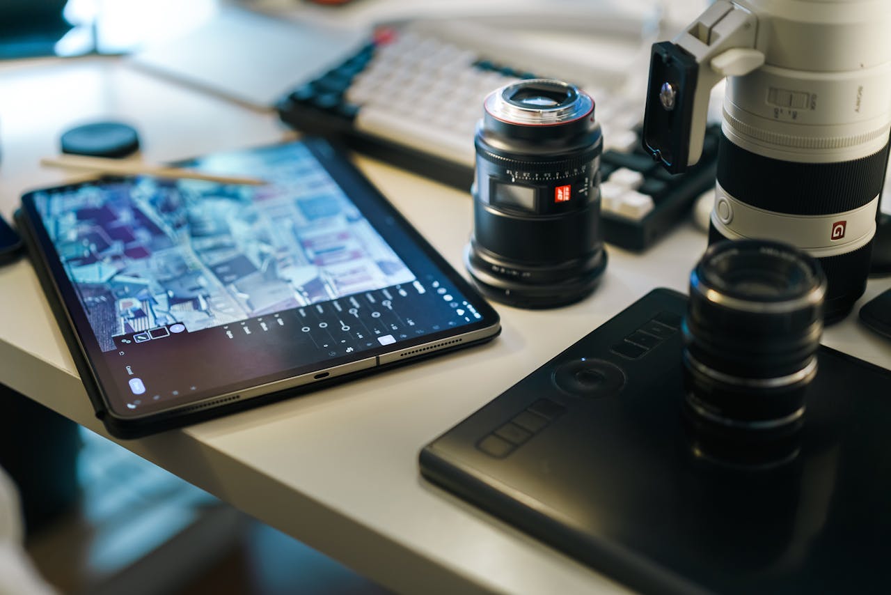 A detailed look at a photography workspace with camera lenses, a digital tablet, and editing software.